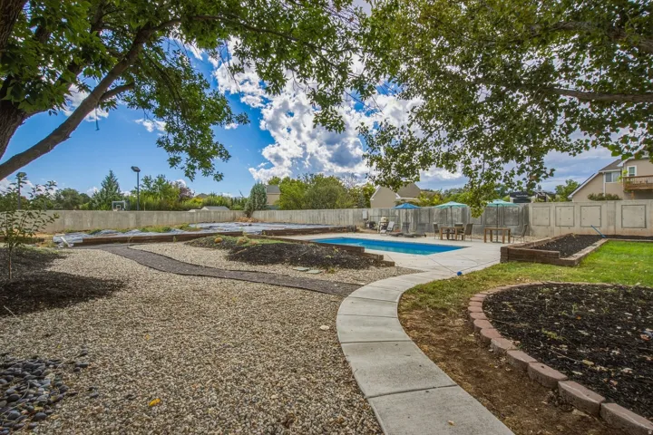 In-ground swimming pool, concrete pool deck, concrete pathway, gravel landscaping, raised garden beds