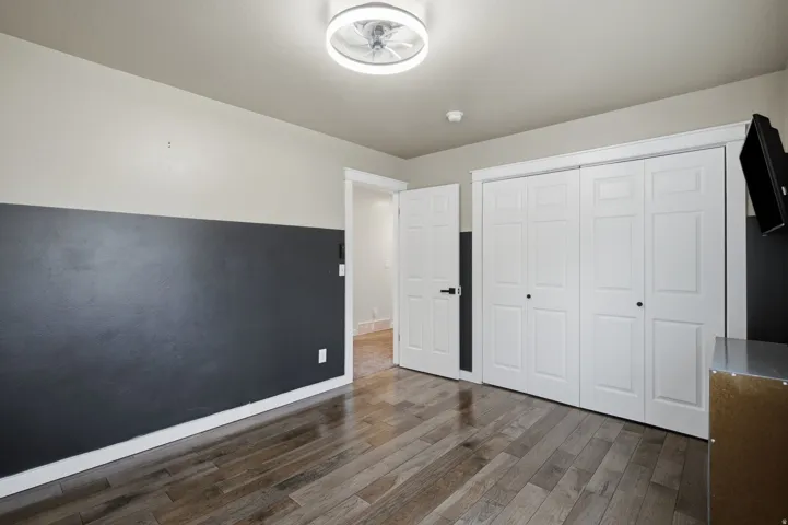 Wood-finish flooring, two-tone wall paint, white trim, white paneled bifold closet doors, and a contemporary ceiling light fixture