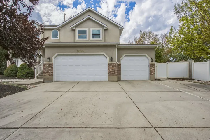 Stucco exterior with brick accents, concrete driveway, and a two-car garage