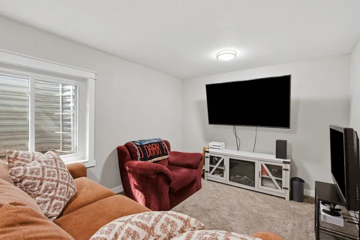 Recessed window with white trim, wall-mounted television, built-in entertainment console with electric fireplace, and textured carpeting