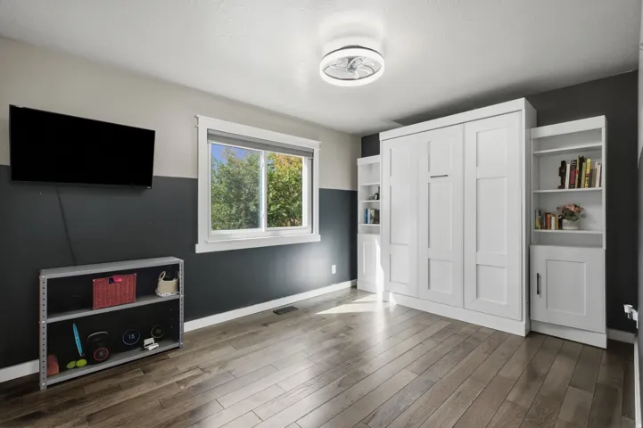 Wood-finish flooring, built-in storage solutions, modern ceiling light fixture, and a large window