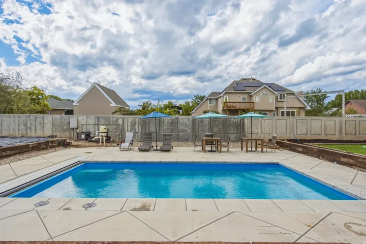 Outdoor swimming pool with a concrete surround and concrete panel fencing