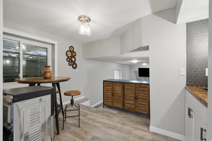 Wood-finish flooring, built-in cabinetry with louvered doors, and a honeycomb tile backsplash