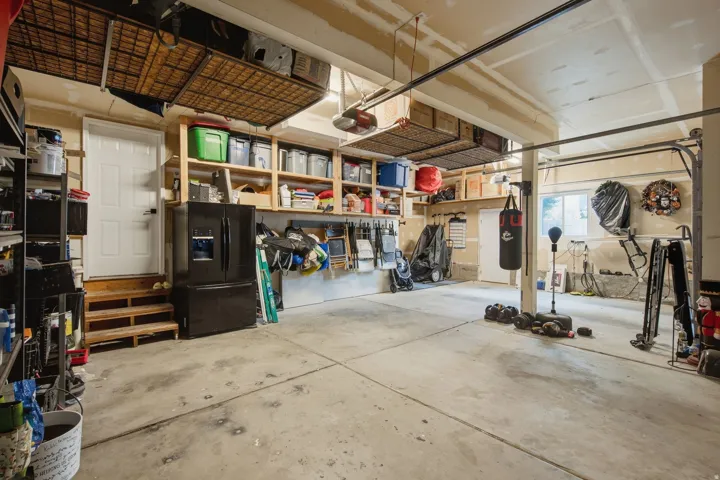 Concrete flooring, overhead storage racks, built-in shelving, white door, and a window providing natural light