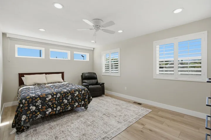 Recessed lighting, ceiling fan, multiple windows with white plantation shutters, three transom windows, wood-finish flooring