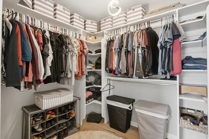 Custom closet system with multiple hanging rods, integrated shelving, and corner storage