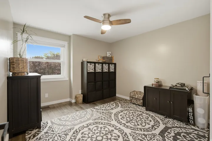 Ceiling fan with integrated lighting, wood-finish flooring, and a window with white trim