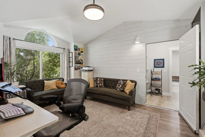 Vaulted ceiling with an arched transom window, shiplap accent wall, wood-finish flooring, and recessed lighting
