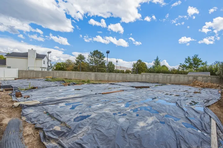 Level lot featuring a concrete retaining wall, a white privacy fence, and mature trees