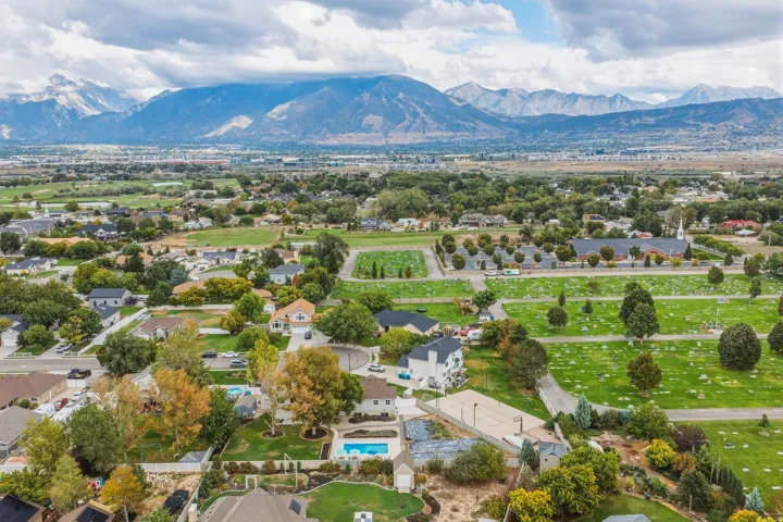 Expansive mountainous backdrop over a residential area with a prominent swimming pool, mature trees, and a hardscaped court