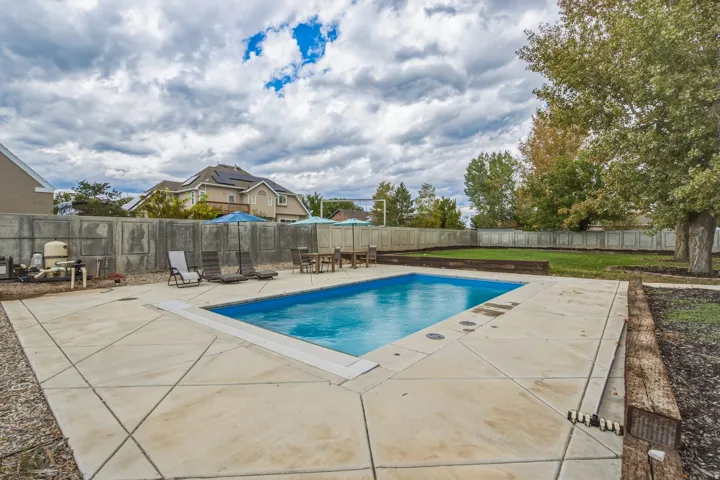 Rectangular inground swimming pool with surrounding concrete decking, and a concrete perimeter fence