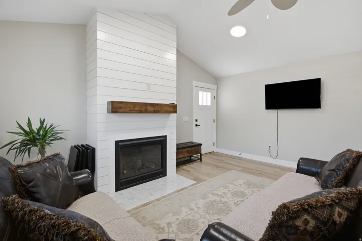 Fireplace with shiplap surround, wood mantle, and tile hearth