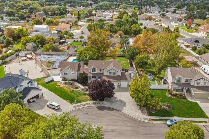 Two-story residence featuring a multi-car driveway, attached garage, and a large front yard with mature trees