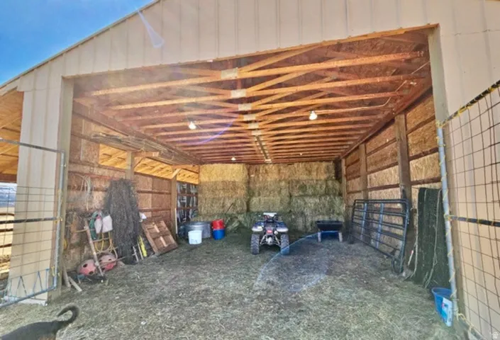 Spacious barn structure featuring a metal exterior, exposed wood beam ceiling, and a large open entry