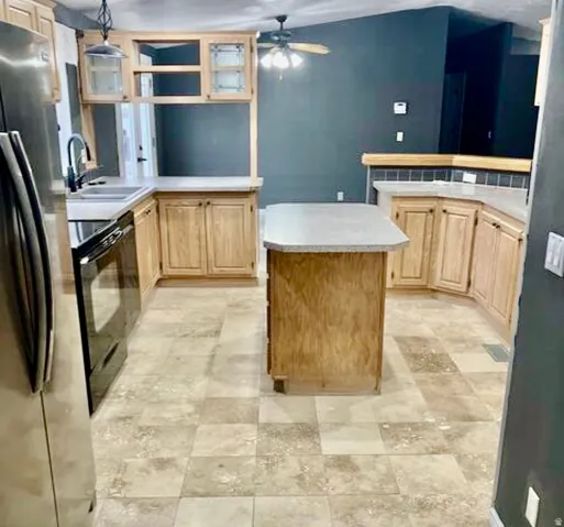 U-shaped kitchen layout featuring light wood-finish cabinetry, solid surface countertops, and an integrated kitchen island