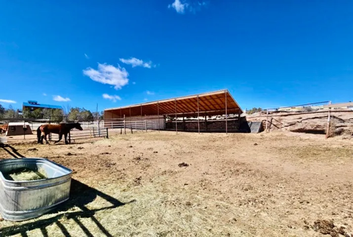 Expansive outdoor area featuring a large covered shelter, multiple fenced enclosures, and natural rock formations