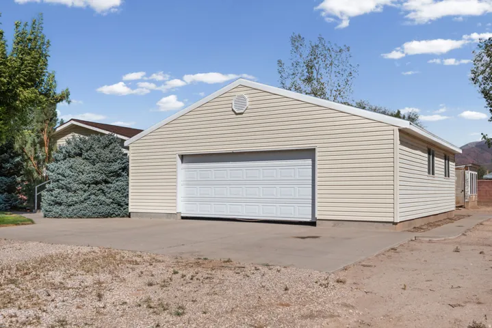 Detached garage with horizontal siding, a white sectional garage door, and a concrete driveway
