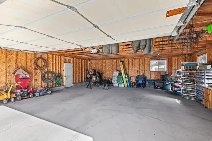 Spacious garage with concrete flooring, exposed wood-finish walls, and a white interior door