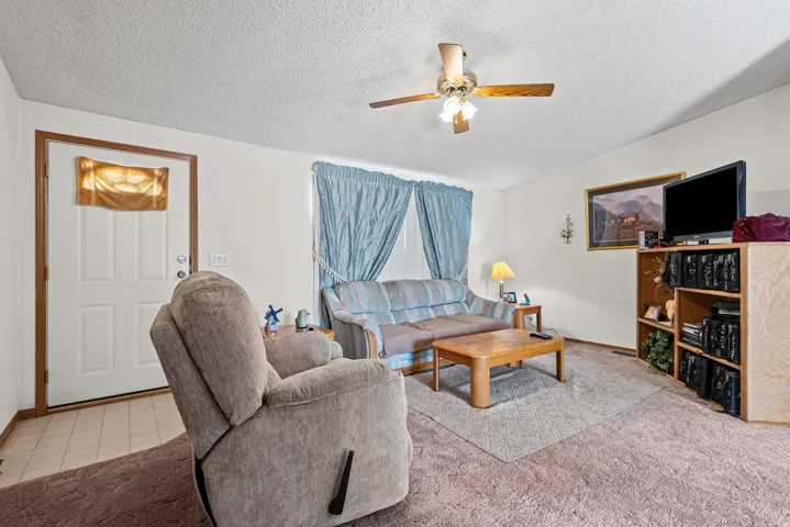 Recessed entry with tile flooring, ceiling fan with integrated lighting, and carpeted living space