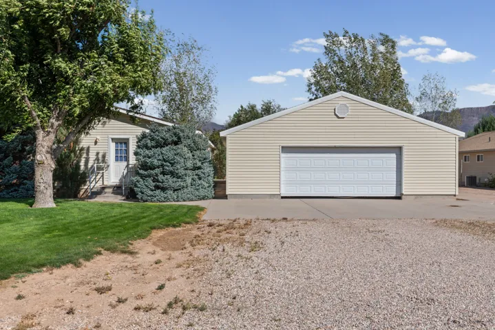 Detached garage with horizontal siding, a white sectional garage door, and a circular vent