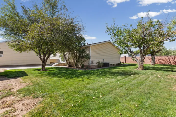 Expansive lawn area with mature trees and a brick privacy wall