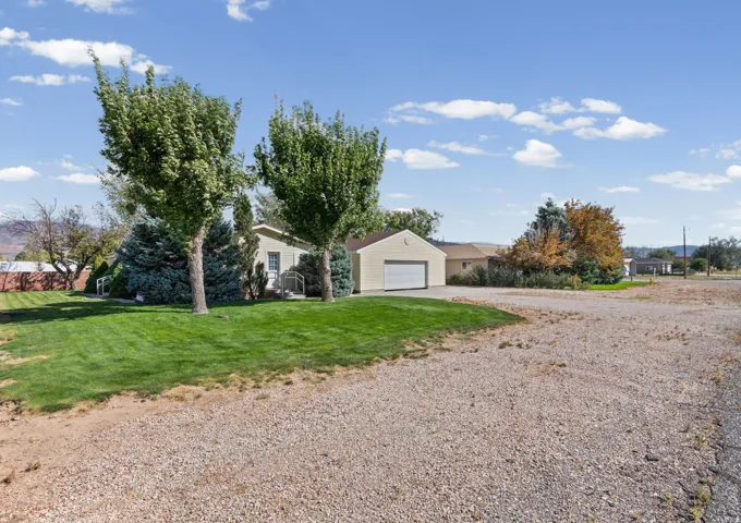 Single-story residence with a light-colored exterior siding, an attached garage, and a gravel driveway