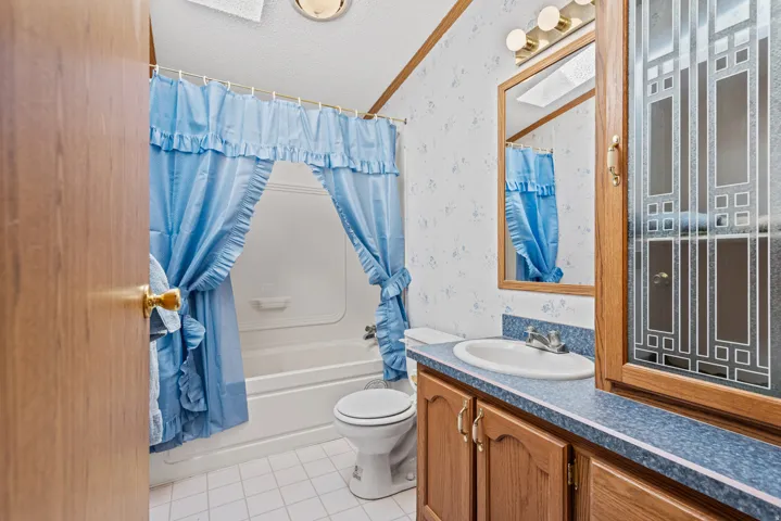 Bathroom featuring a built-in vanity with wood-finish cabinetry, a single basin sink, and a framed mirror
