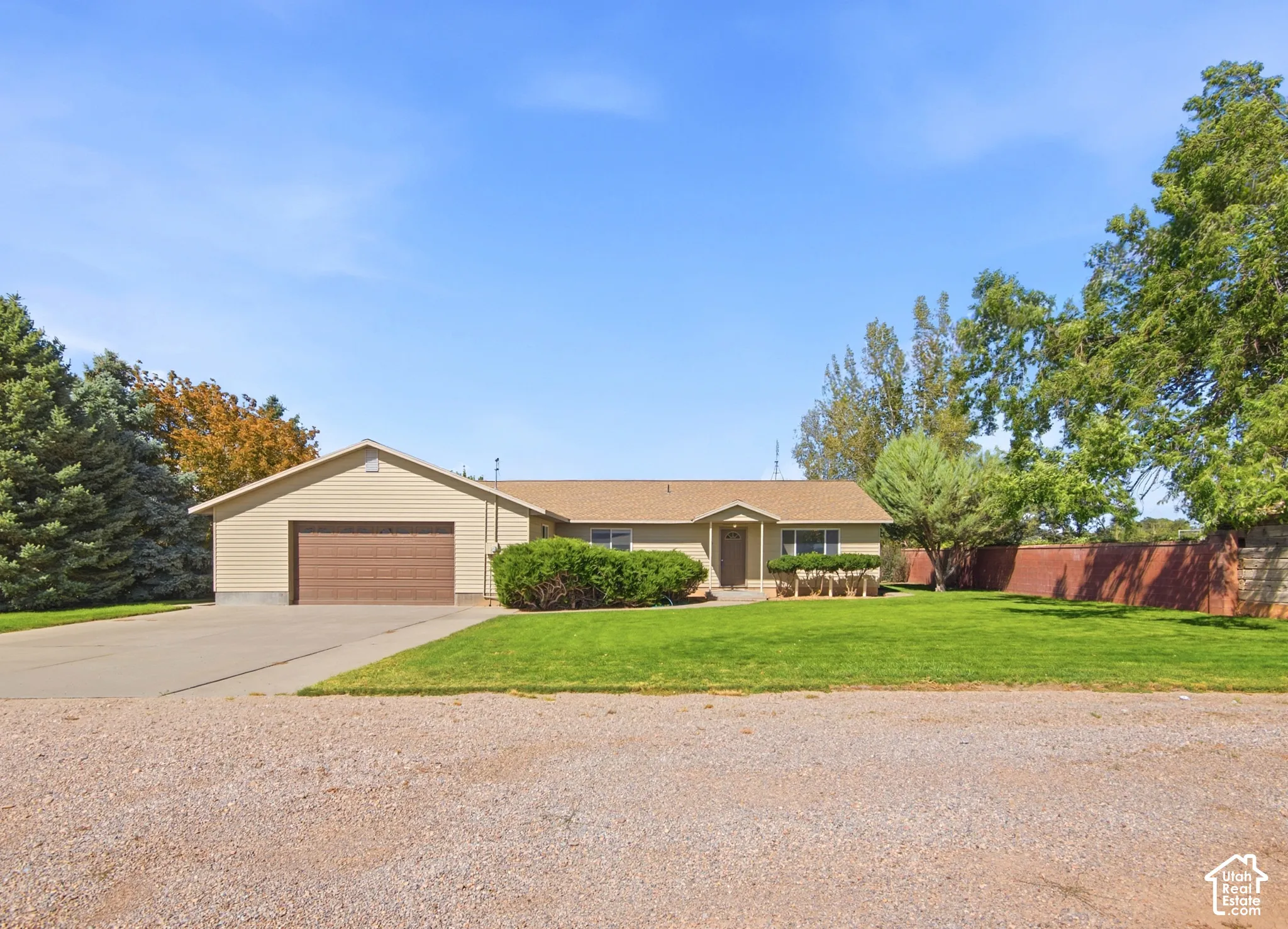 Single-level residence featuring horizontal siding, a gabled roof, an attached two-car garage, a concrete driveway, and a fenced yard
