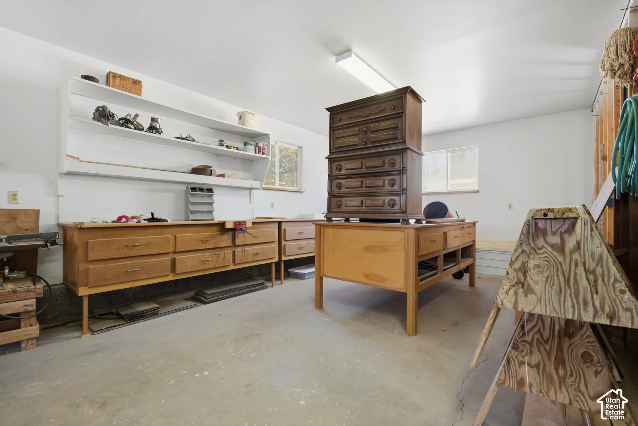 Concrete flooring, white walls, built-in shelving, windows, and fluorescent lighting