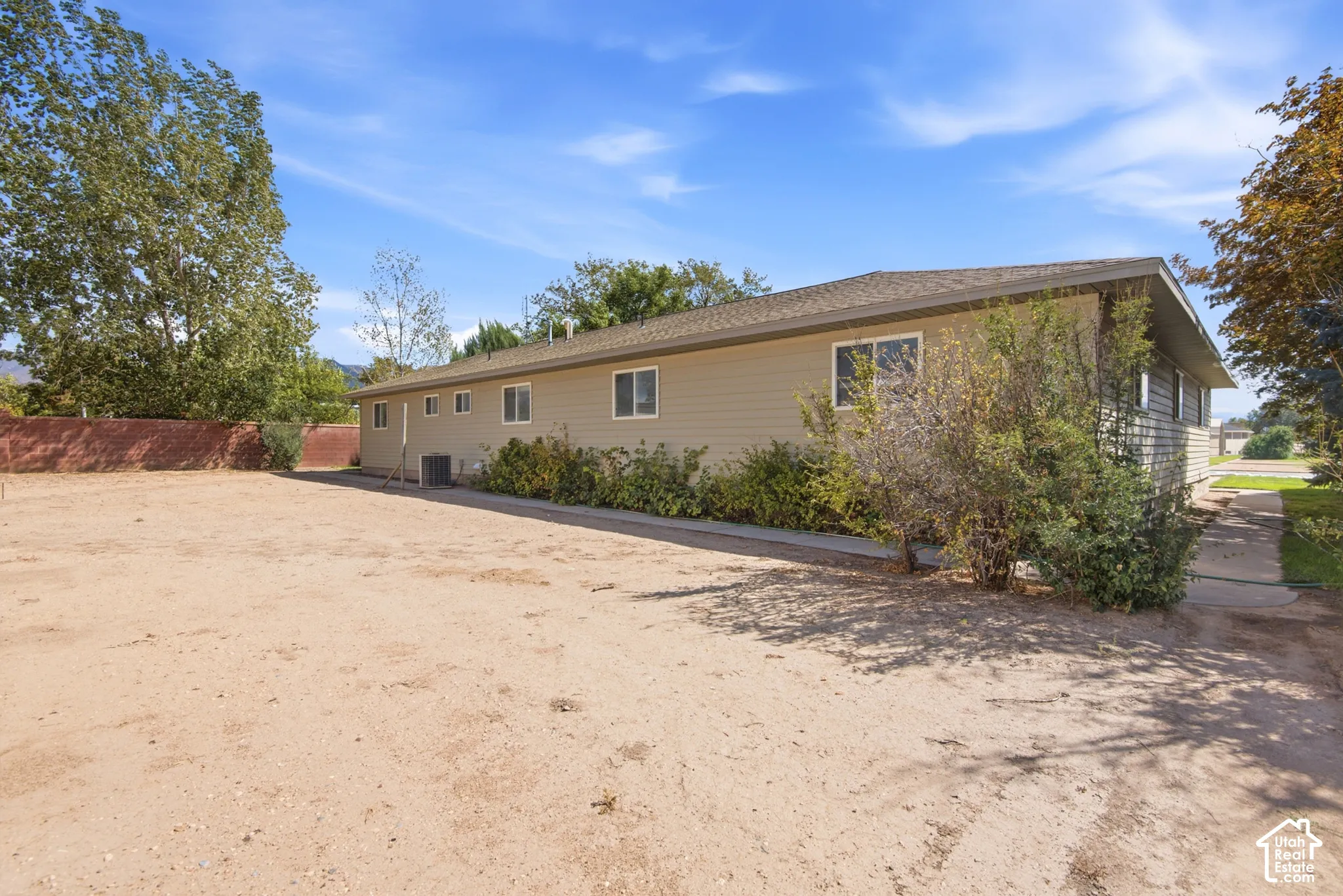 Siding exterior with multiple windows, mature landscaping, and a concrete perimeter