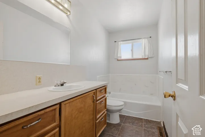 White vanity with wood-finish cabinetry, integrated sink, and an overhead vanity light