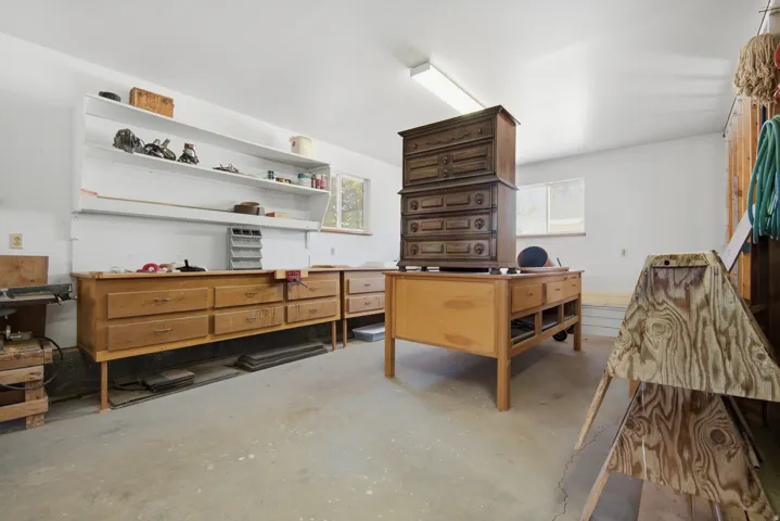 Concrete flooring, white walls, built-in shelving, windows, and fluorescent lighting