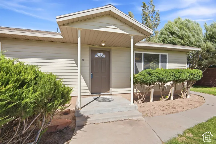 Covered front entry with concrete steps and walkway