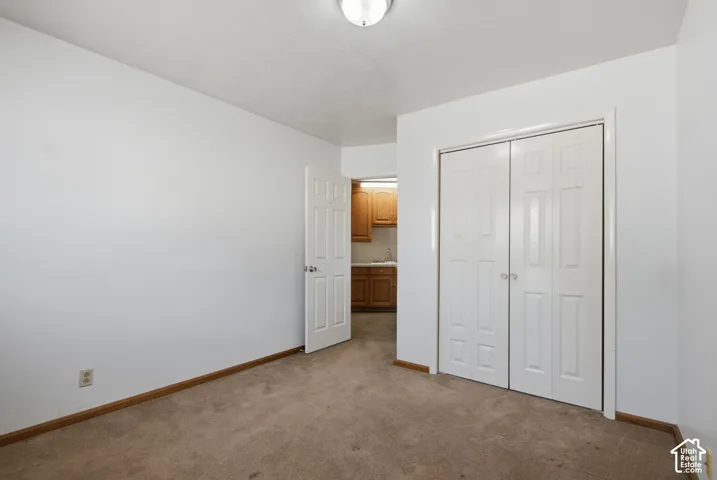 Carpeted room with a ceiling-mounted light fixture, white walls, and bi-fold closet doors