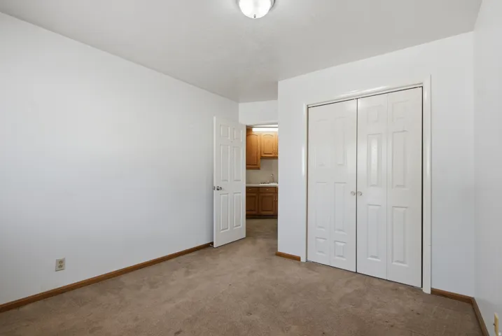 Carpeted room with a ceiling-mounted light fixture, white walls, and bi-fold closet doors