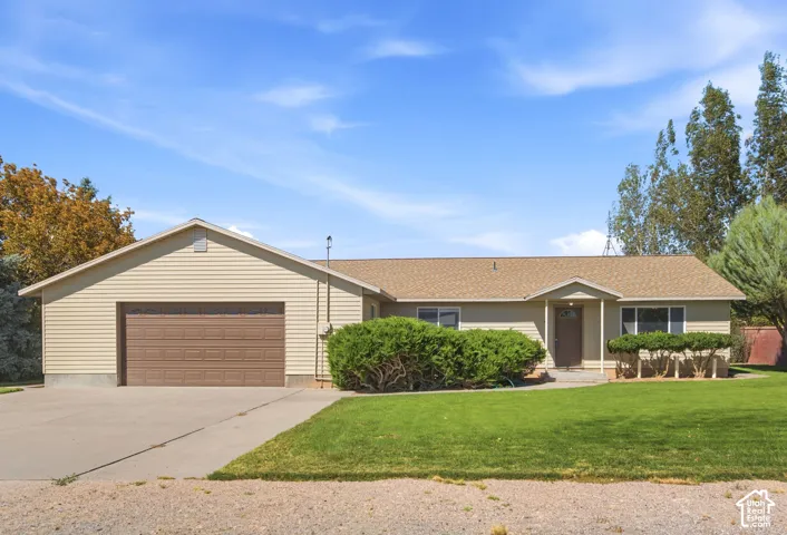 Single-story ranch exterior featuring vinyl siding, an attached two-car garage, and an expansive front lawn