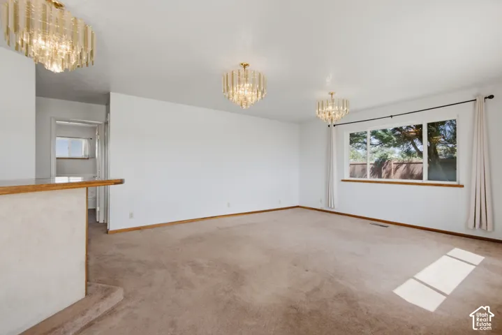 Wall-to-wall carpeting, three contemporary chandeliers, and a large window with wood trim