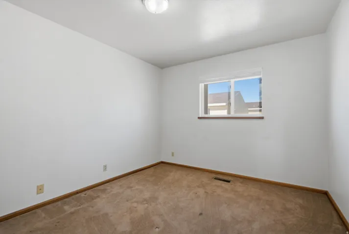 Recessed window with wood-finish sill, neutral wall color, and carpeted flooring