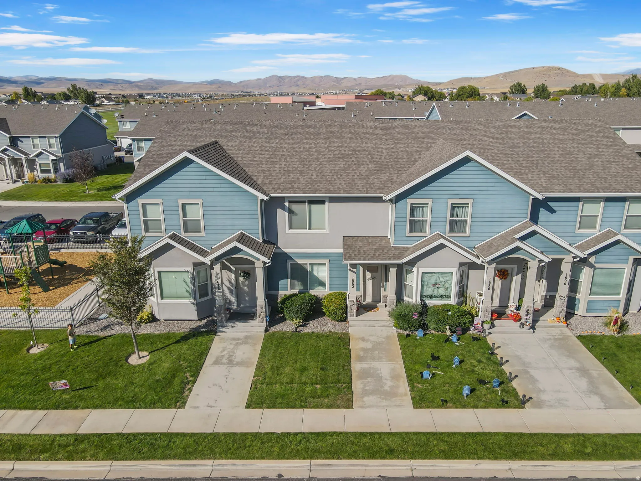 Townhome exterior featuring blue siding, grey stone accents, covered entryways, and a private yard space