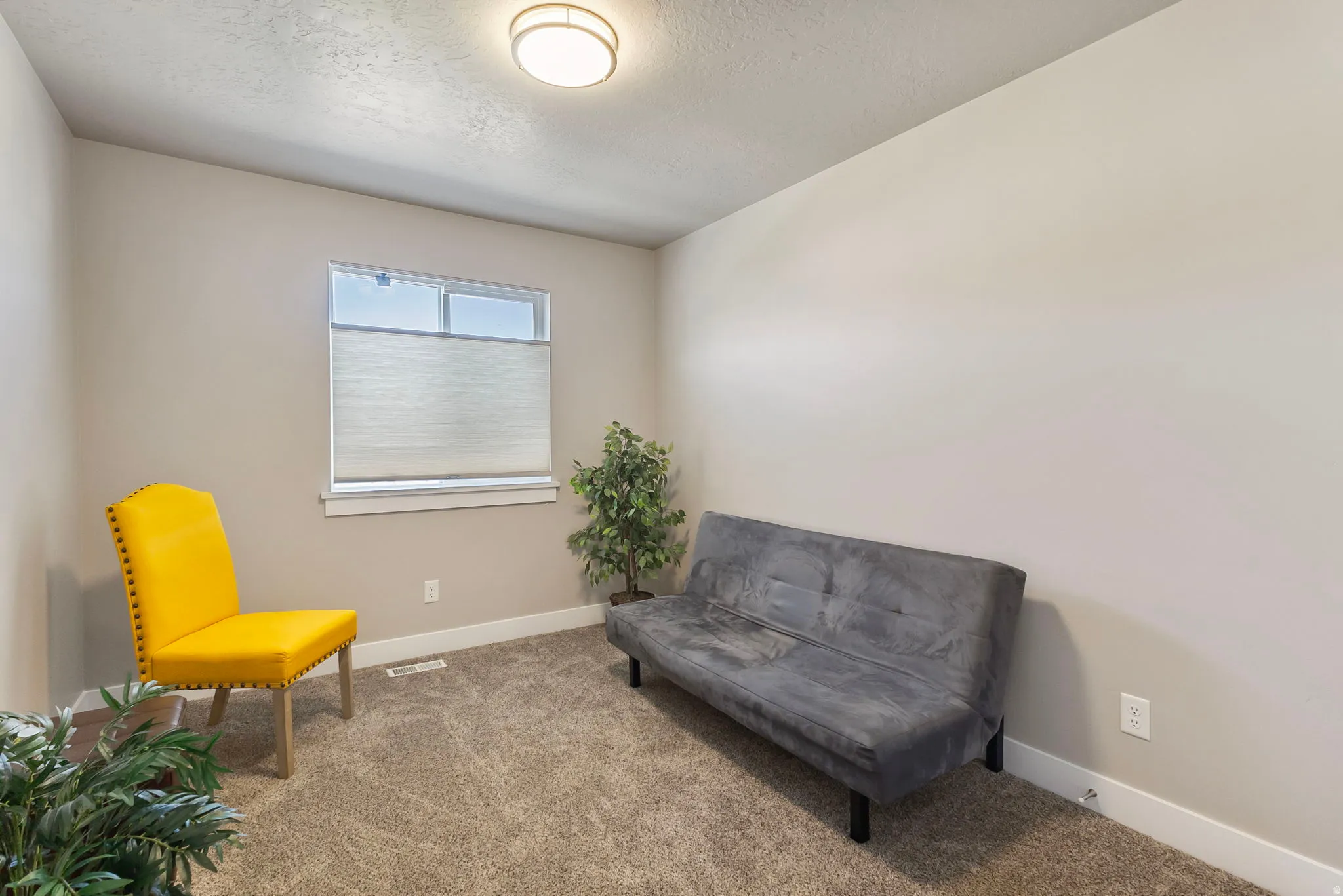 Wall-to-wall carpeting with neutral wall tones and a single window featuring a cellular shade