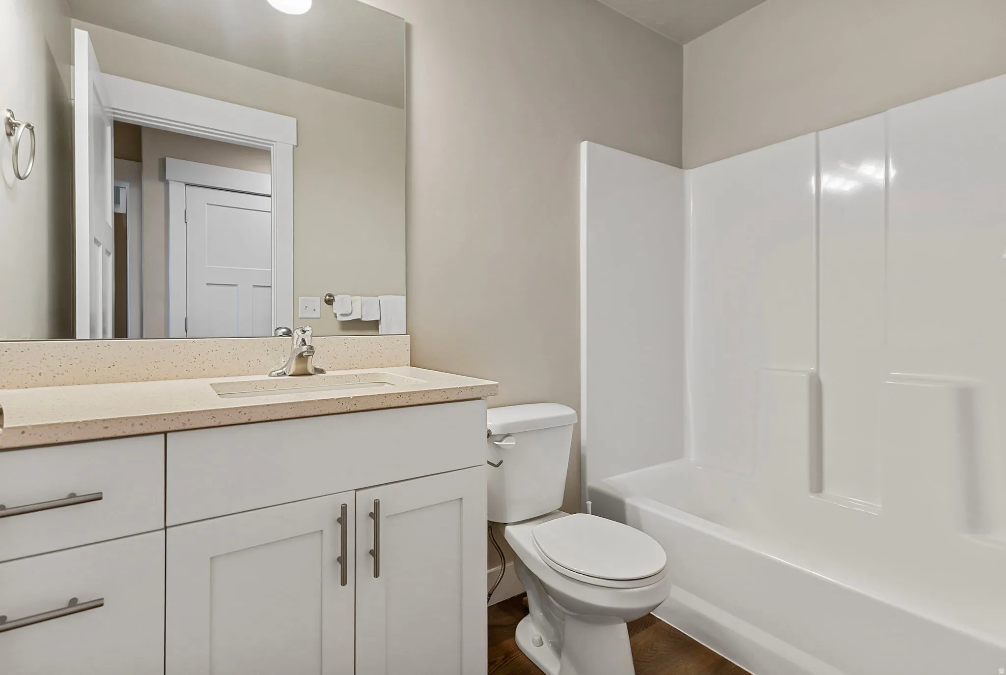 White vanity with brushed nickel hardware, integrated sink, and speckled countertop