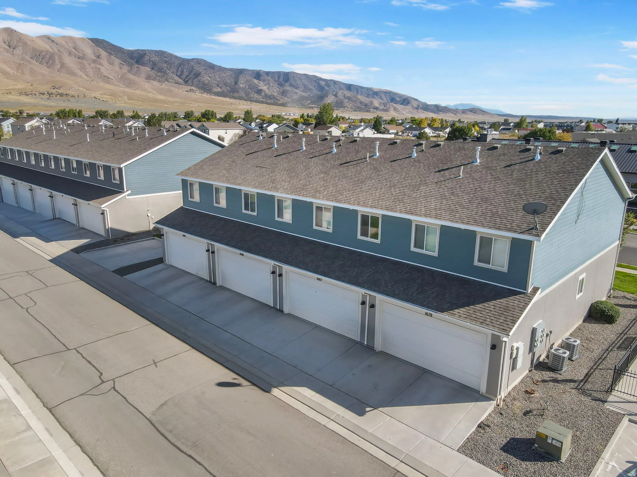 Townhome-style residences featuring light blue siding, grey shingle roofs, and individual garages