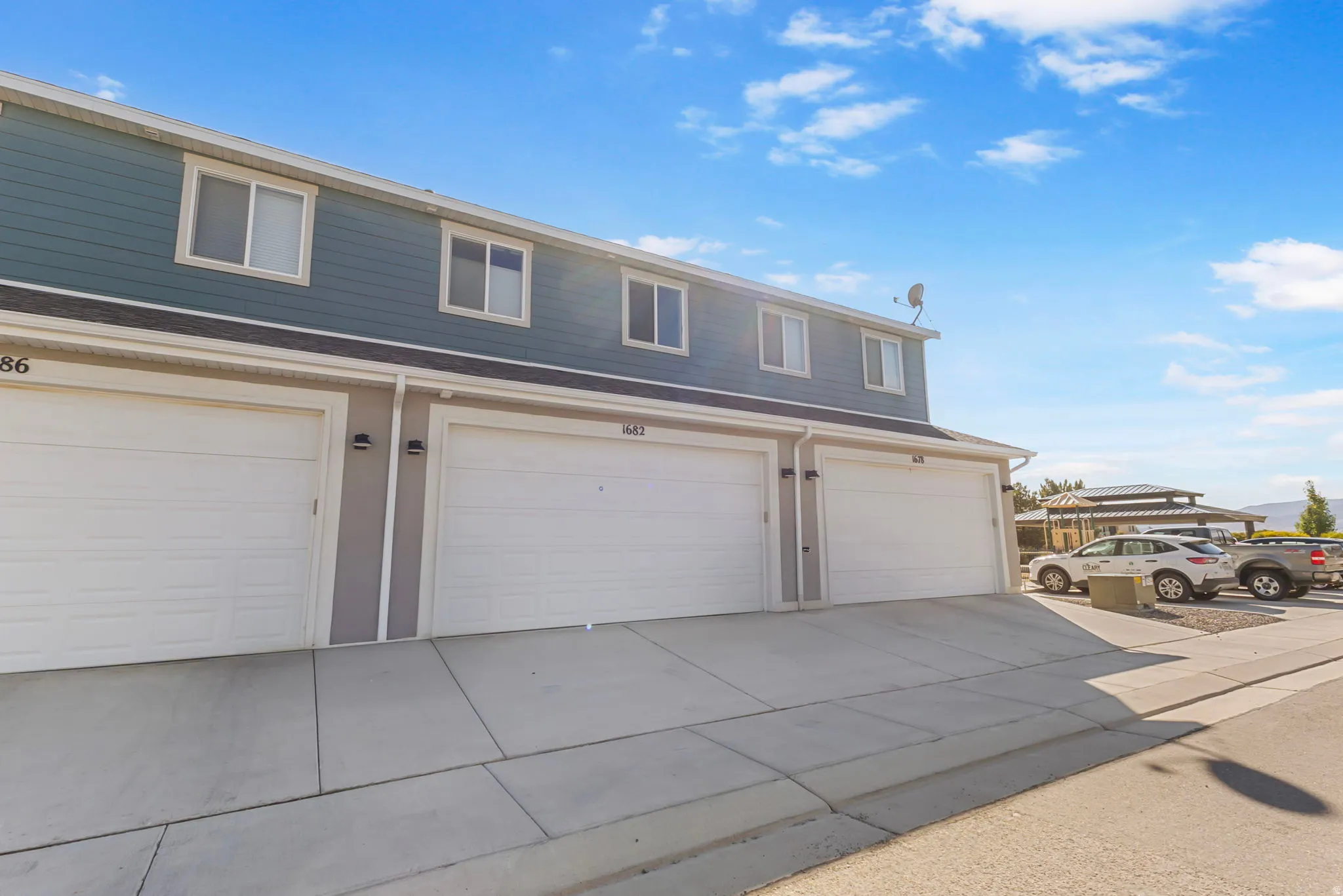 Two-story exterior with horizontal siding, multiple windows, and individual garage doors
