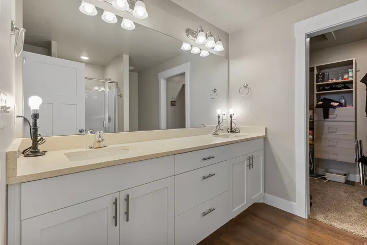 Double vanity with light-toned countertop, dual undermount sinks, and contemporary wall-mounted lighting