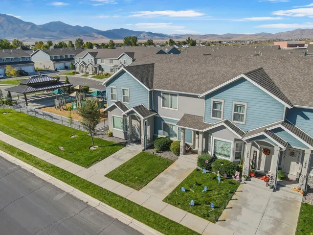 Two-story townhome with a light blue and gray exterior, featuring a private driveway, covered front porch, and a bay window