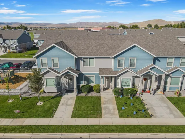 Townhome exterior featuring blue siding, grey stone accents, covered entryways, and a private yard space