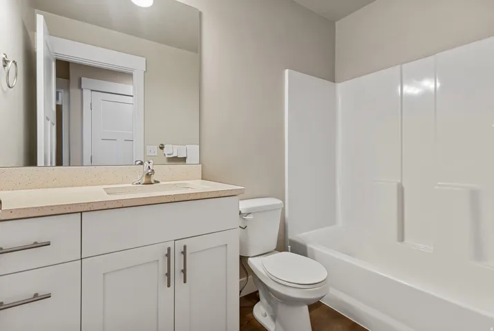 White vanity with brushed nickel hardware, integrated sink, and speckled countertop