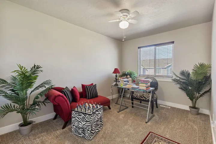 Carpeted interior space with a ceiling fan, a window with blinds, and light-toned walls