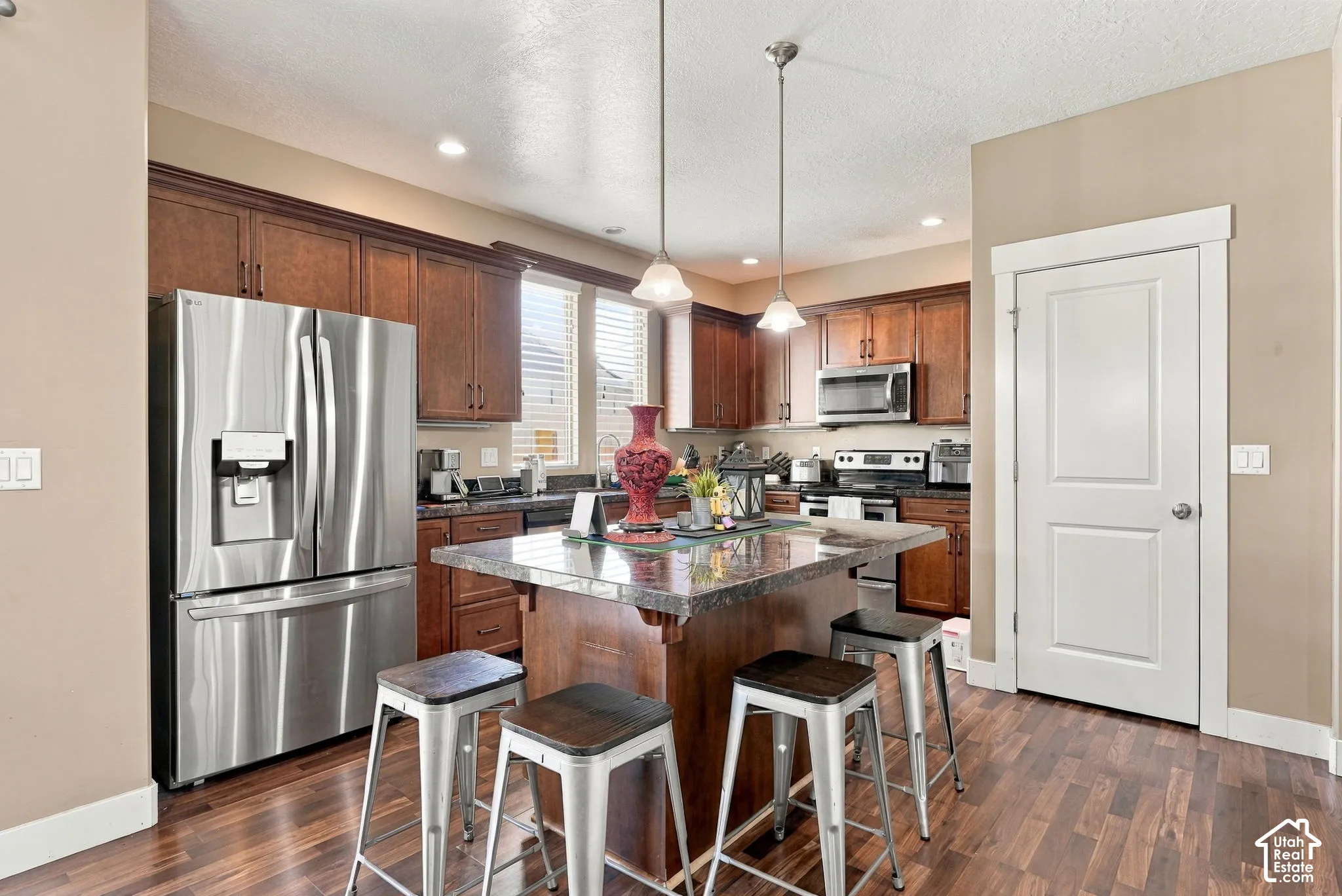 Kitchen with wood-finish flooring, dark wood cabinetry, a center island with countertop seating, stainless steel appliances, and recessed lighting