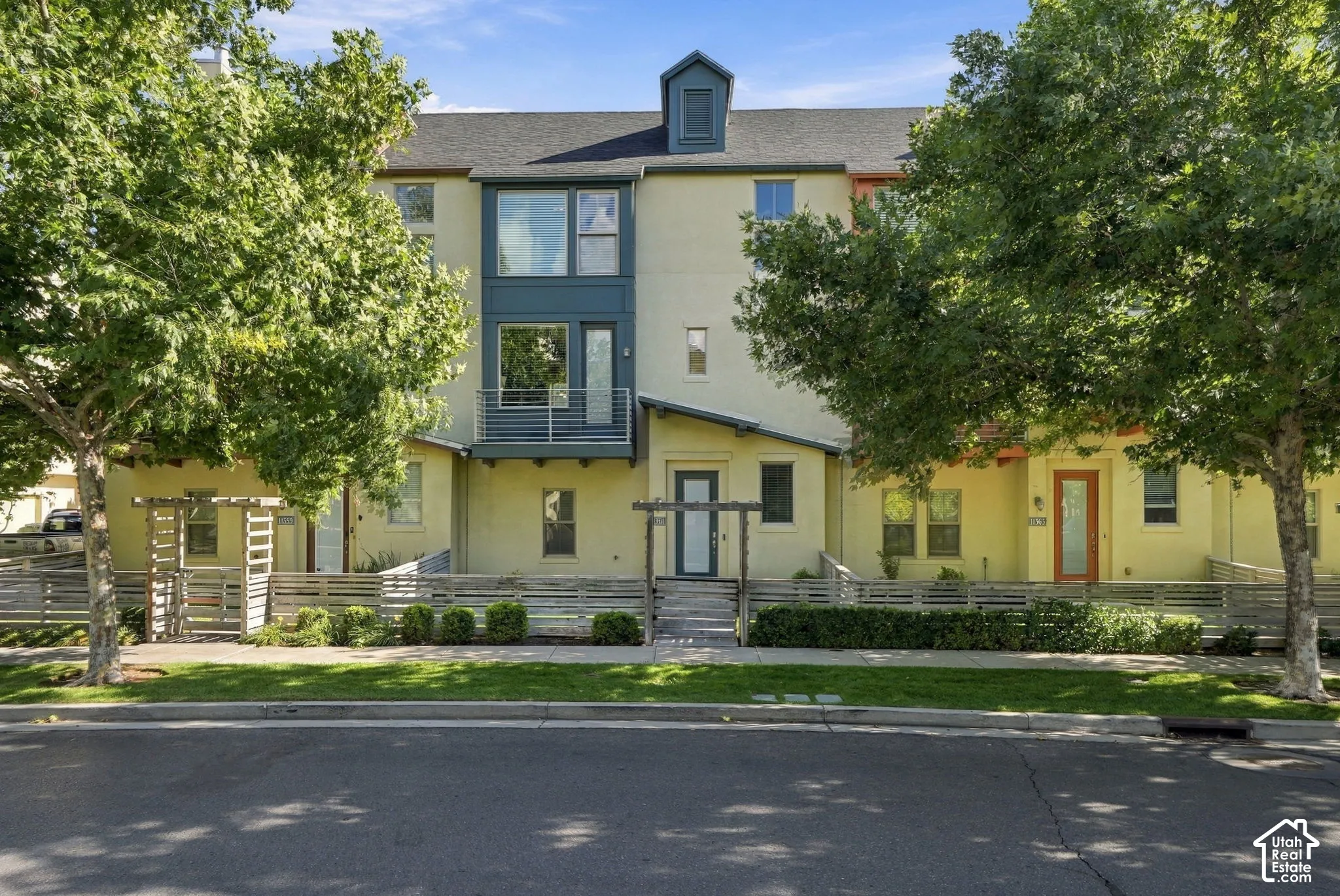 Contemporary townhome with a stucco exterior, multi-story windows, and a private balcony with metal railings